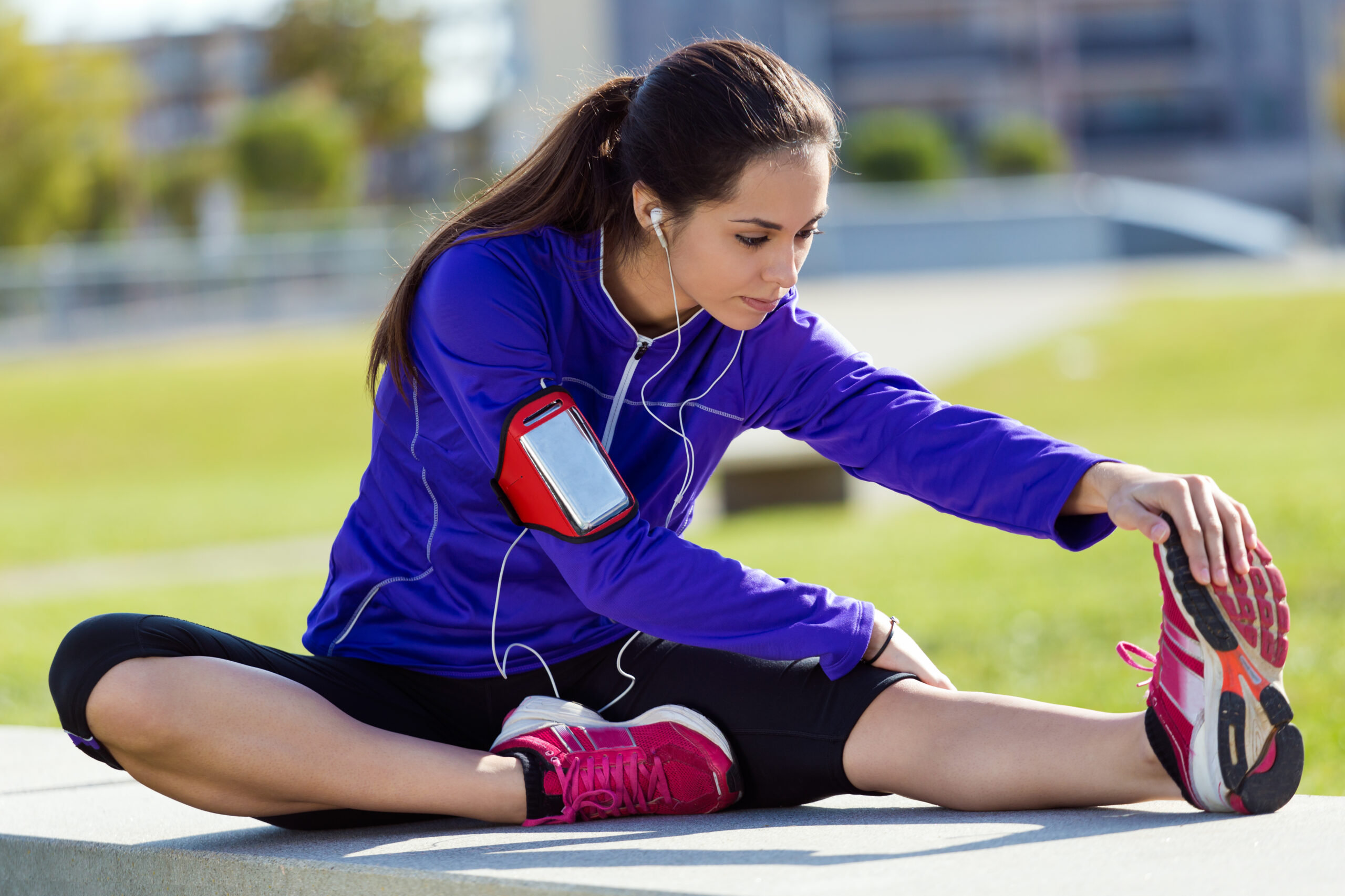 Outdoor portrait of young woman stretching and preparing for running.